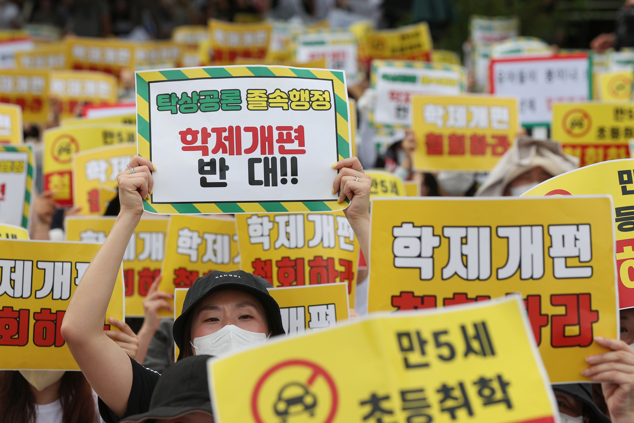 Členové občanských skupin drží v pondělí odpoledne před válečným památníkem v Yongsan-gu v Soulu cedule s nápisem „Žádná reforma školského systému“ a skandují během shromáždění proti vládnímu plánu snížit věk pro vstup do základní školy na 5 let.