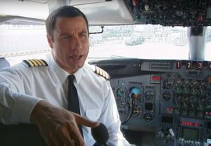 John Travolta jako pilot v kokpitu letadla